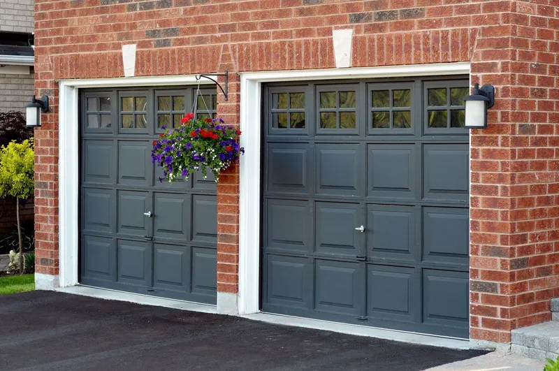 Pair of dark grey up and over garage doors on a brick house